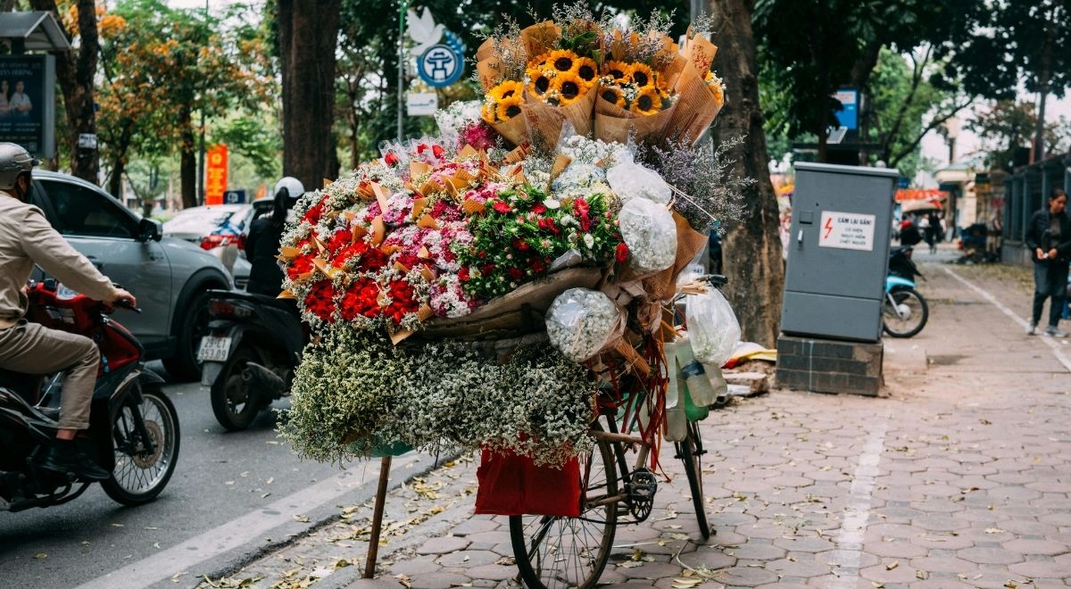 Des vendeuses ambulantes transportant des fleurs colorées dans les rues de Hanoï en fin d’année.